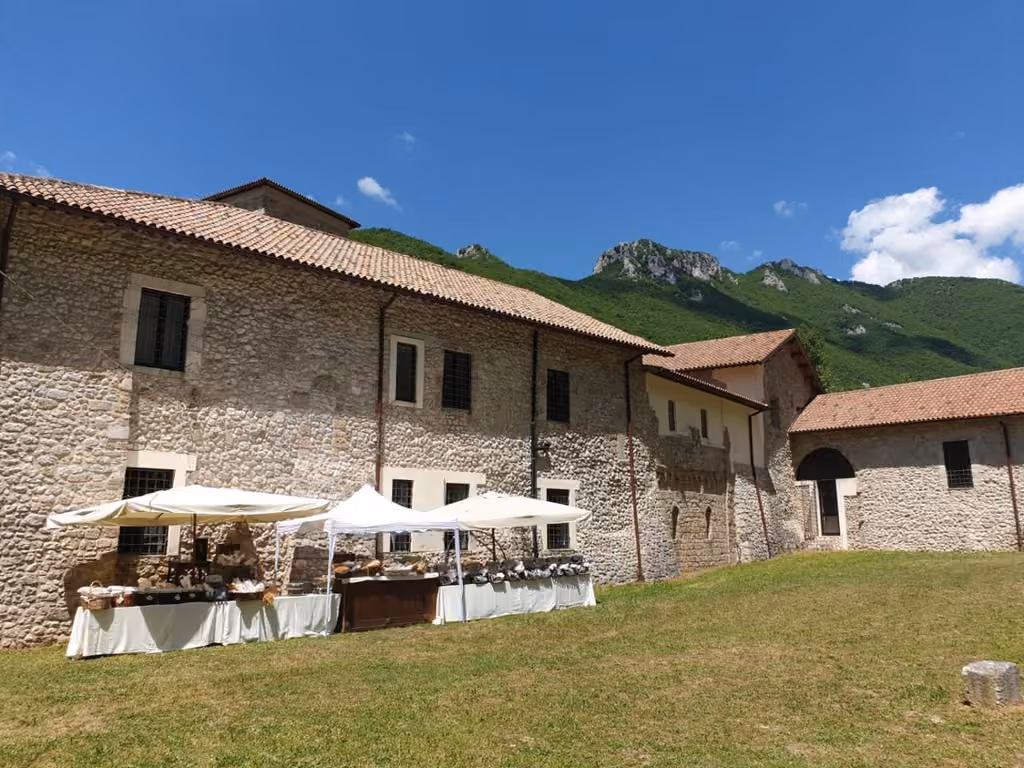 Due tavoli con ombrelloni davanti all'edificio dell'abbazia